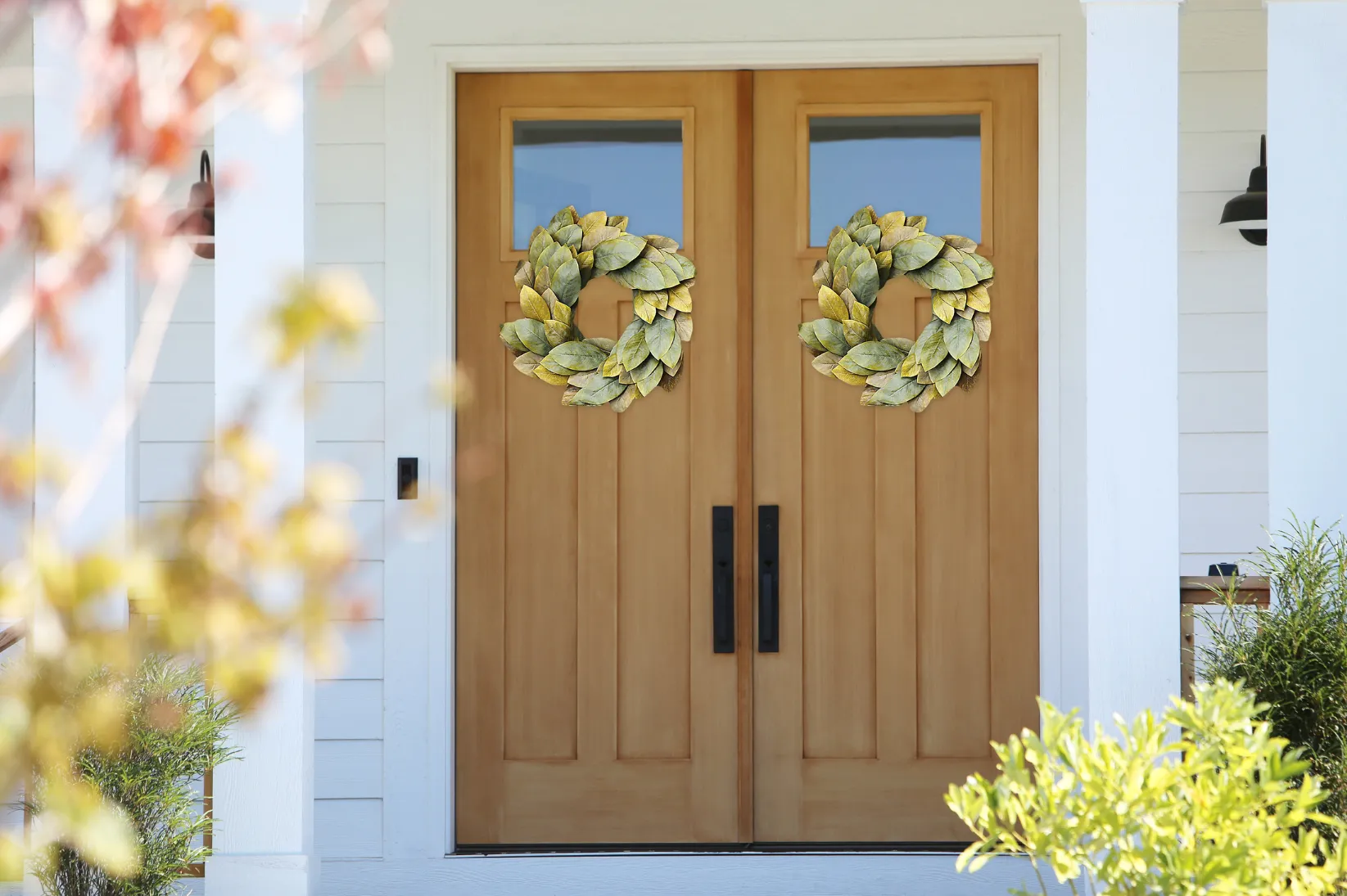 Two wooden doors with wreaths, front porch.
